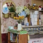 A shelf with books, flowers, and decorative items.